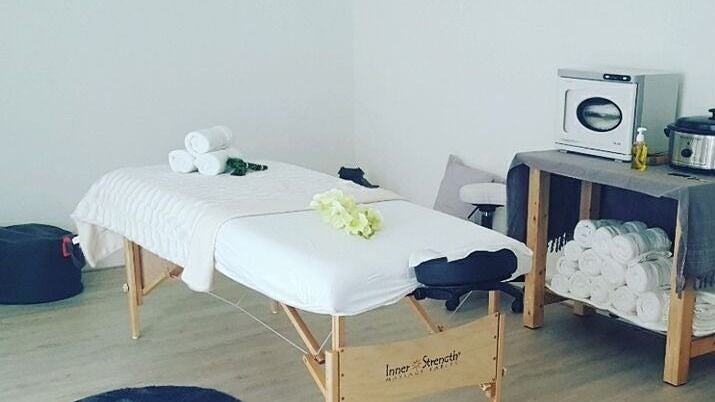 De massagetafel met opgerolde handdoeken en de handdoekenwarmer ernaast